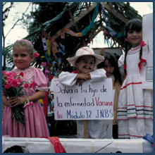 Three children hold signs and ride in back of truck during immunization parade