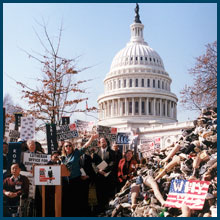 Jody Williams with a group of protestors march in front of U.S. Capitol Building while holding banners and signs.