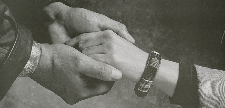 A poster with text and a black and white photograph of hands holding