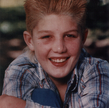 Color photograph of a smiling white boy (Ricky Ray) sitting in the grass