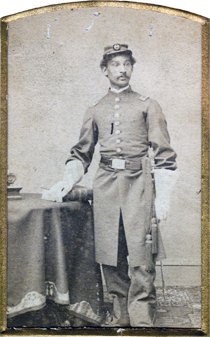 Black and white photograph with gold border showing Anderson R. Abbott in a military union wearing a hat and gloves with one hand resting on a table beside him. Courtesy Toronto Public Library, Abbott Collection.