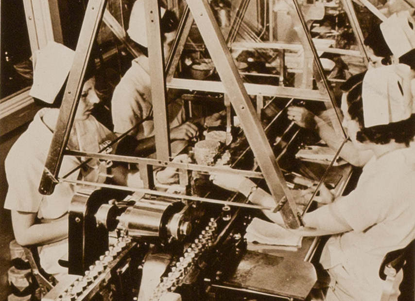 Photo of women workeds filing and sealingn vials.