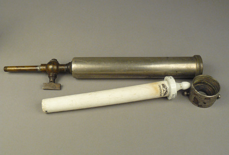 White ceramic filter tube with nipple on one end and metal pipe-like case for the ceramic filter. 