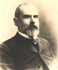 Black and white photograph head and shoulders, right pose, full face of Julian John Chisholm in a suit.