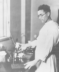 A man in scrubs inserts a needle into a test tube in a laboratory.