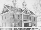 Exterior view of the two-story empty school building in Hmailton, Montana with the sign U. S. Public Health Service Laboratory above the steps leading inside.