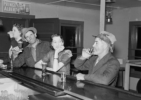 Black and white photograph of four people drinking alcohol at a bar.