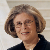 Dr. Constance Urciolo Battle, a White female with short hair in professional attire posing on a marble staircase.