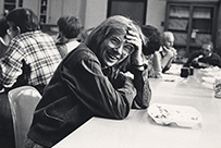 Dr. Ruth Harriet Bleier, a smiling female seated with a cafeteria tray in front of her. Her hand rests on her forehead.