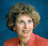 Dr. Joanne Froio Domson, a White female in a coral jacket gazing to her left for a portrait.