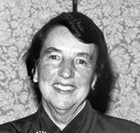 Dr. Helen Hofsommer Glaser, a smiling White female in a blouse with a boutonniere.