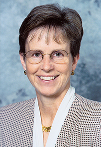 Dr. Ann Connor Jobe, a White female with cropped hair and glasses posing for portrait.