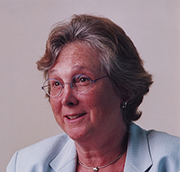 Dr. Mary Margaret Kemeny, a smiling White female in a light blur suit seated with her hands folded in front of her.