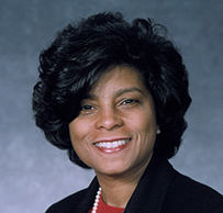 Dr. Risa J. Lavizzo-Mourey, a female with dark short hair in a red louse and dark jacket posing for her portrait.