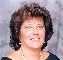 Dr. Maria Iandolo, a White female with curly hair wearing a long beaded necklace posing for her portrait.