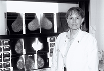 Dr. Marilyn A. Roubidoux, a White female in a lab coat posing next to a set of x-rays.