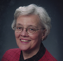 Dr. Eleanor Gossard Shore, a White female in a red and black blouse smiling for her portrait.