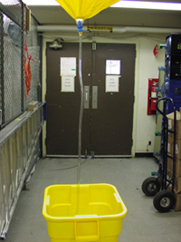 A leak diverter hangs from the ceiling.  The plastic tubing is sending any water from the leak down into a bucket on the floor.